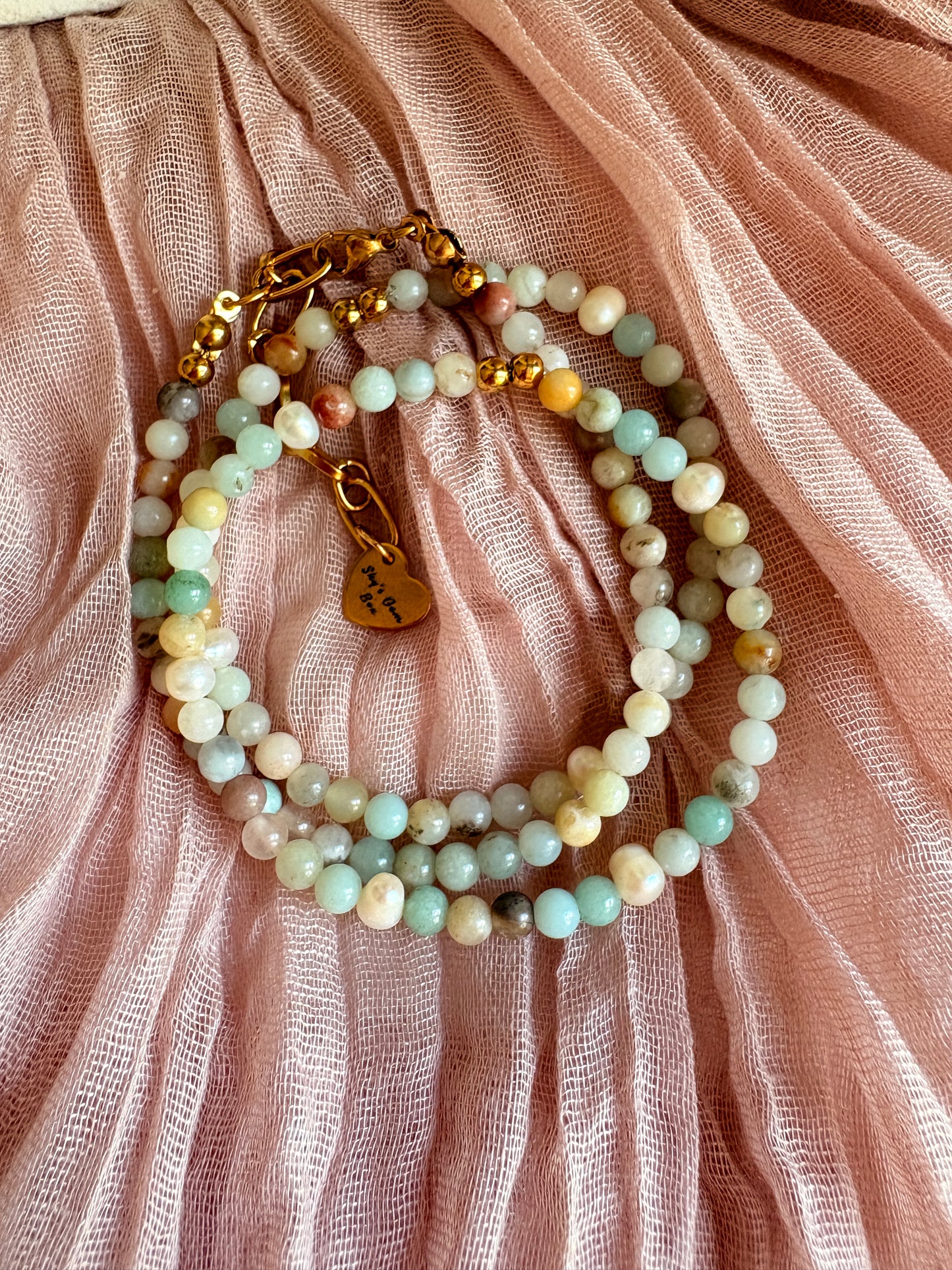 Beaded bracelet with gold accents on a pink fabric background